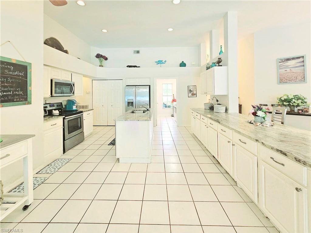 6708 Sloane Place Naples, FL 34104 - Photo 5 of 31 a large white kitchen with a stove a sink dishwasher and a refrigerator with white cabinets