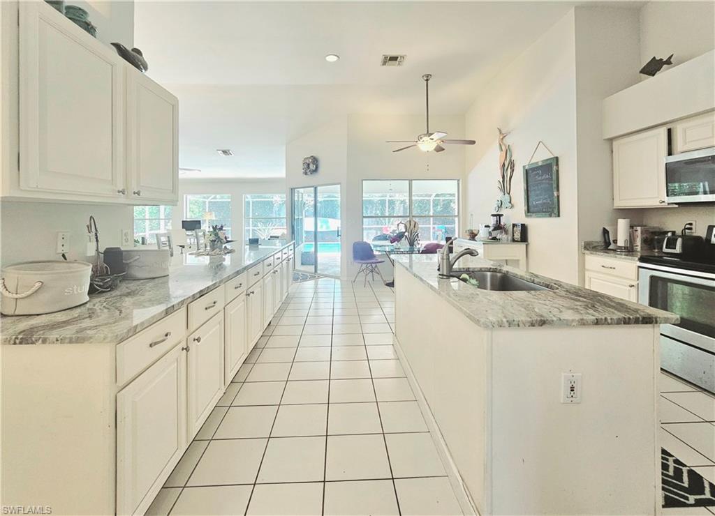 6708 Sloane Place Naples, FL 34104 - Photo 6 of 31 a large kitchen with granite countertop a sink white cabinets and a granite counter tops
