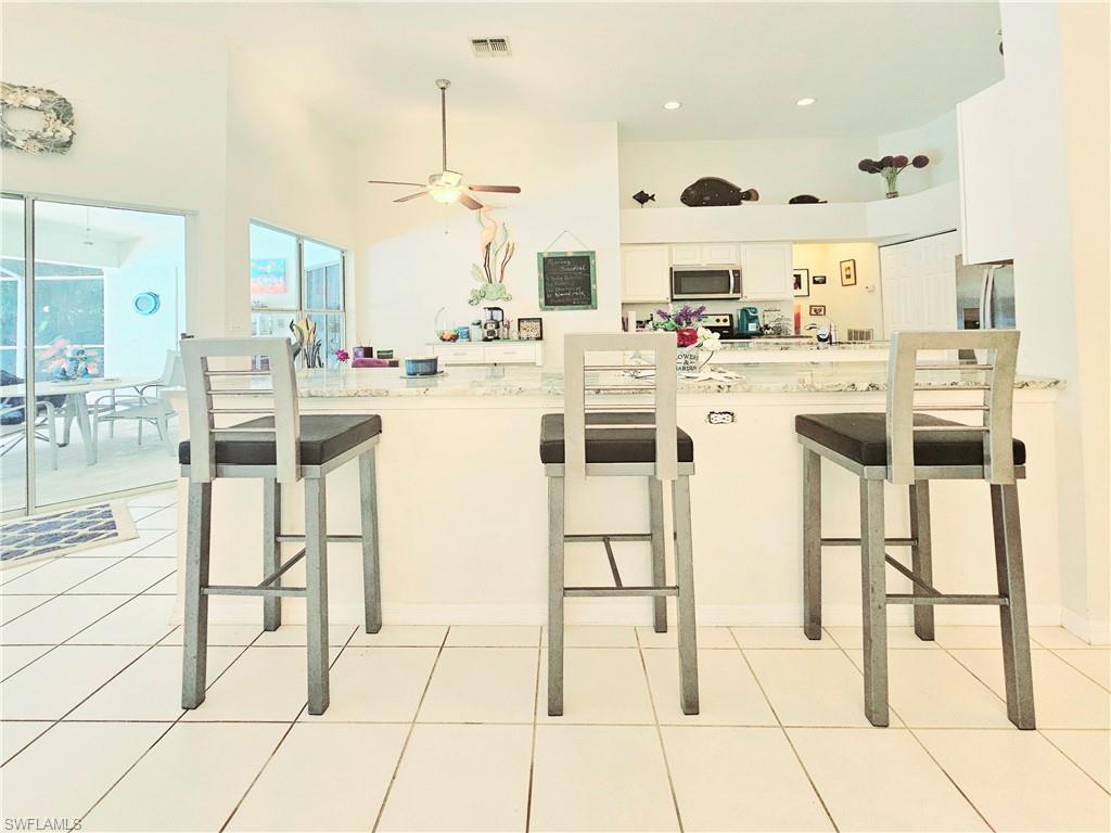 6708 Sloane Place Naples, FL 34104 - Photo 8 of 31 a kitchen with stainless steel appliances kitchen island granite countertop a stove a sink and white cabinets
