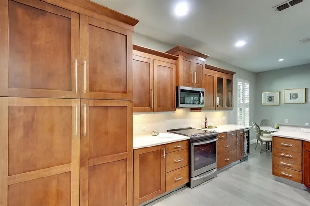 a kitchen with stainless steel appliances granite countertop a stove a sink and a refrigerator with wooden cabinets