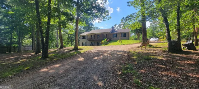 a view of a house with large trees and a yard