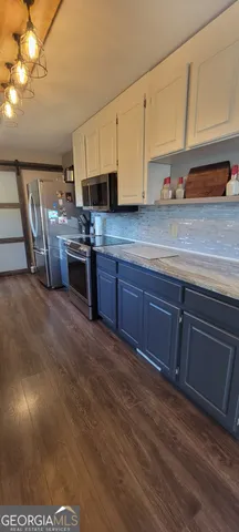 a kitchen with stainless steel appliances granite countertop a sink a stove cabinets and wooden floor