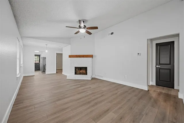 a view of empty room with wooden floor and fireplace