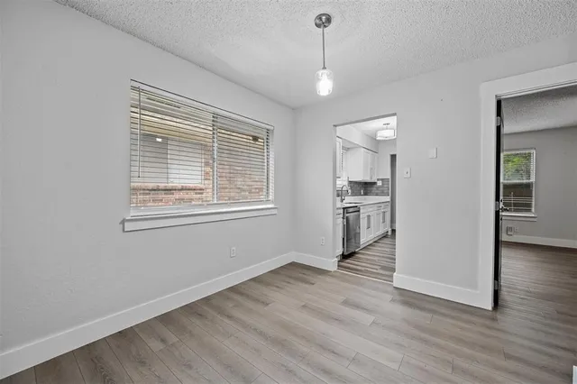 a view of a kitchen and an empty room with wooden floor and a window