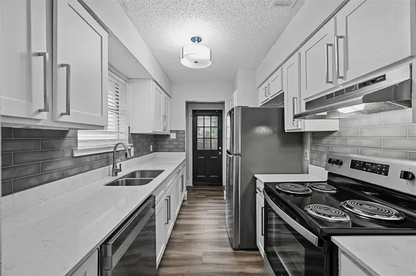 a kitchen with stainless steel appliances granite countertop a stove a sink dishwasher and a refrigerator