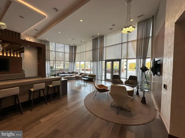 a living room with couches chairs and kitchen view with wooden floor