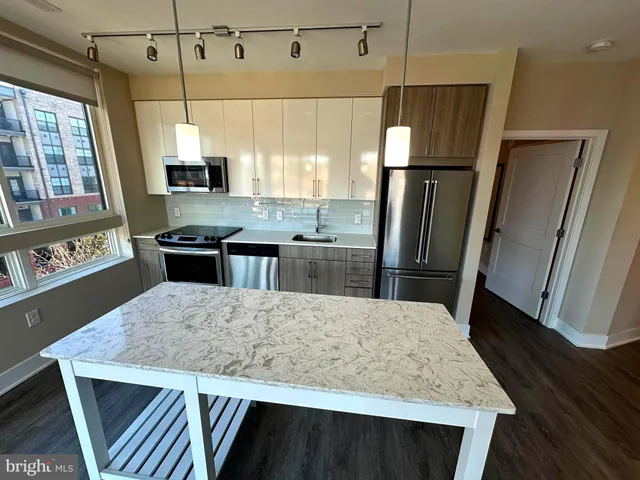 a kitchen with stainless steel appliances granite countertop a sink a refrigerator a microwave a stove and white cabinets