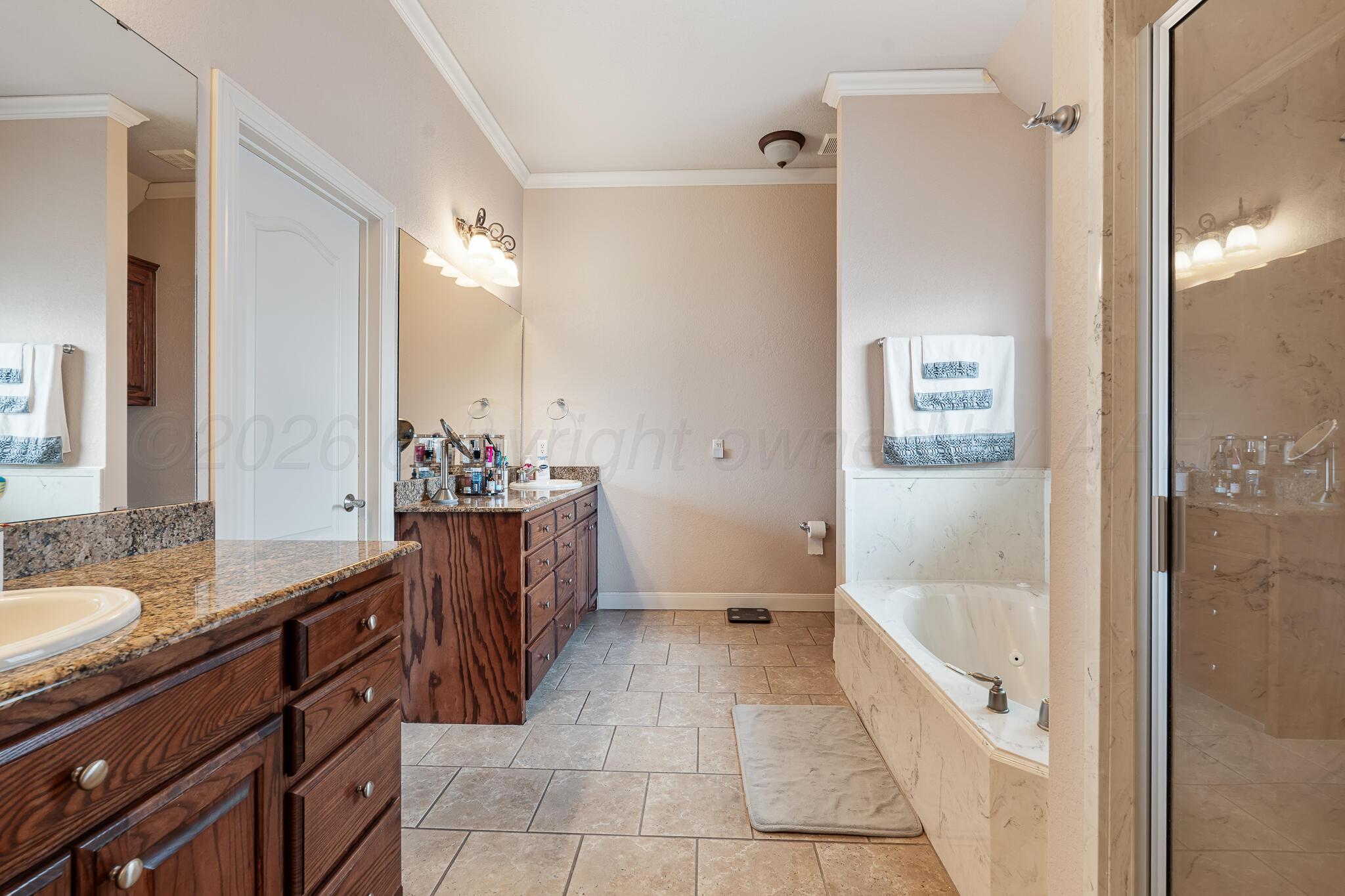 5008 Wesley Road Amarillo, TX 79119 - Photo 29 of 47 a bathroom with a granite countertop sink a mirror and a bathtub