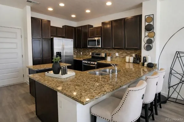 a kitchen with stainless steel appliances granite countertop a sink refrigerator and cabinets