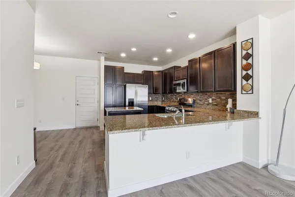 a kitchen with stainless steel appliances granite countertop a sink refrigerator and cabinets