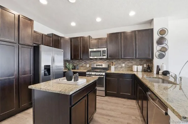 a kitchen with a sink a stove a refrigerator a center island and cabinets