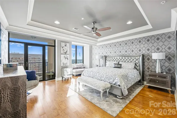 a spacious bedroom with a bed a flat screen tv and balcony view