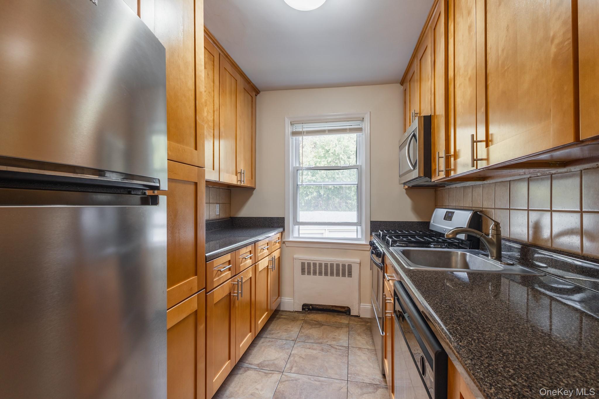 251-41 71st Road, Unit 54B Queens, NY 11426 - Photo 11 of 20 a kitchen with a sink a stove and cabinets