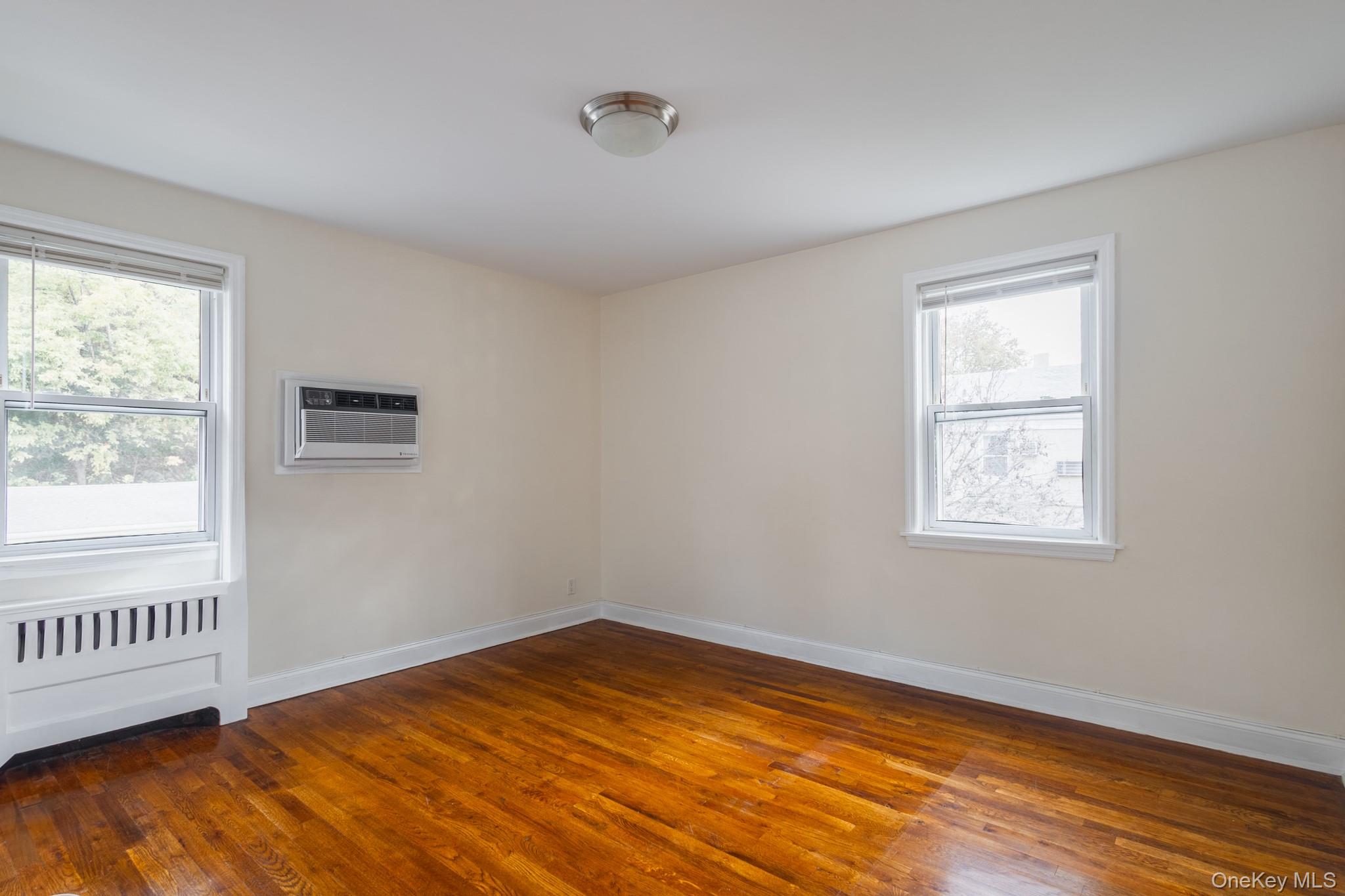 251-41 71st Road, Unit 54B Queens, NY 11426 - Photo 13 of 20 a view of an empty room with wooden floor and a window