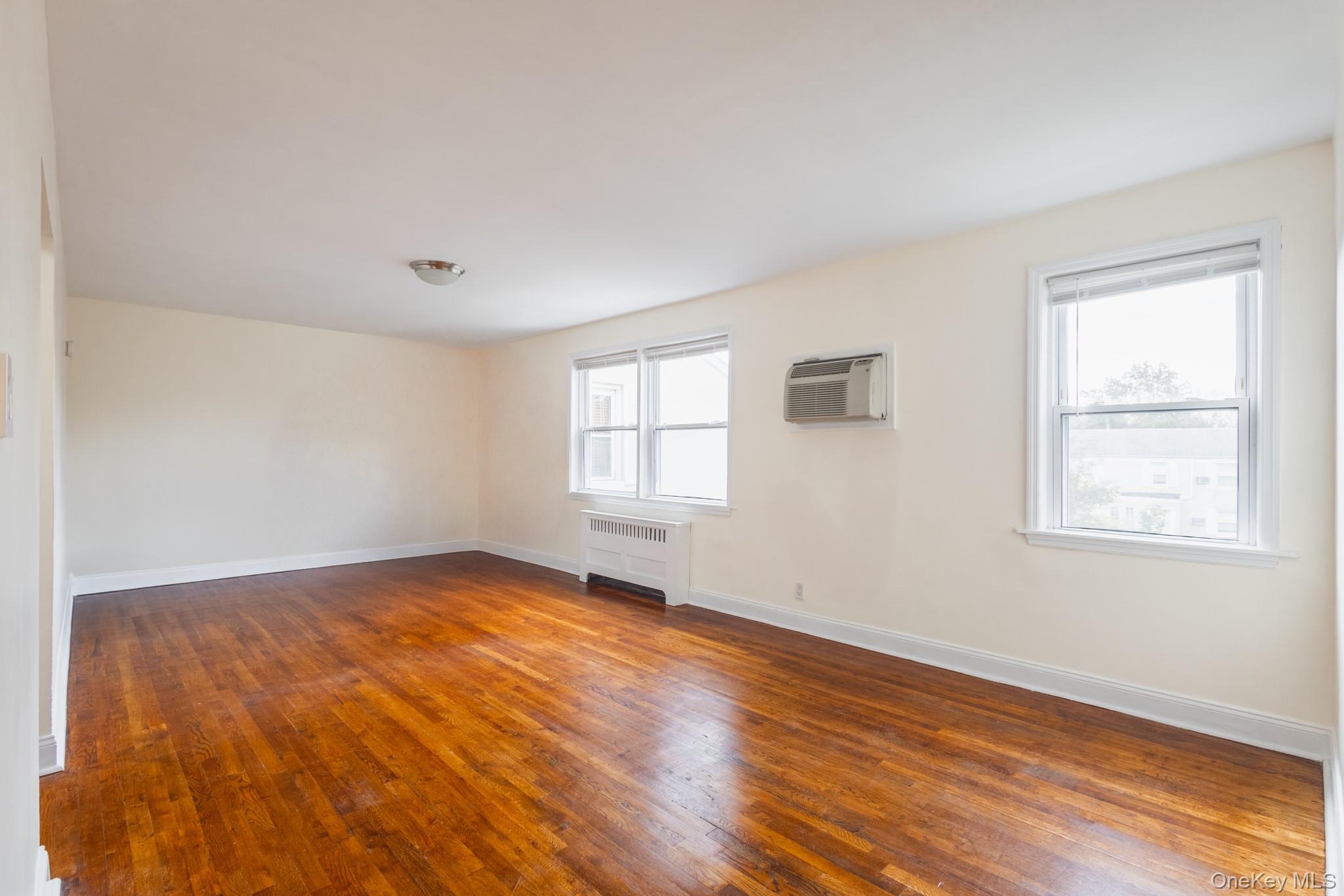 251-41 71st Road, Unit 54B Queens, NY 11426 - Photo 8 of 20 a view of an empty room with wooden floor and a window