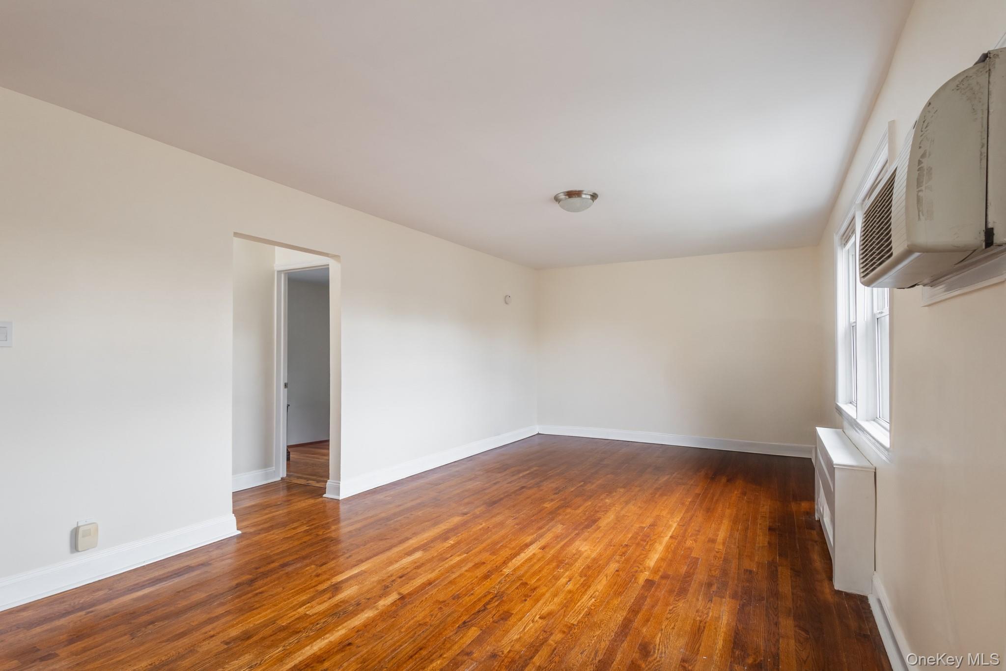 251-41 71st Road, Unit 54B Queens, NY 11426 - Photo 9 of 20 an empty room with wooden floor and a window