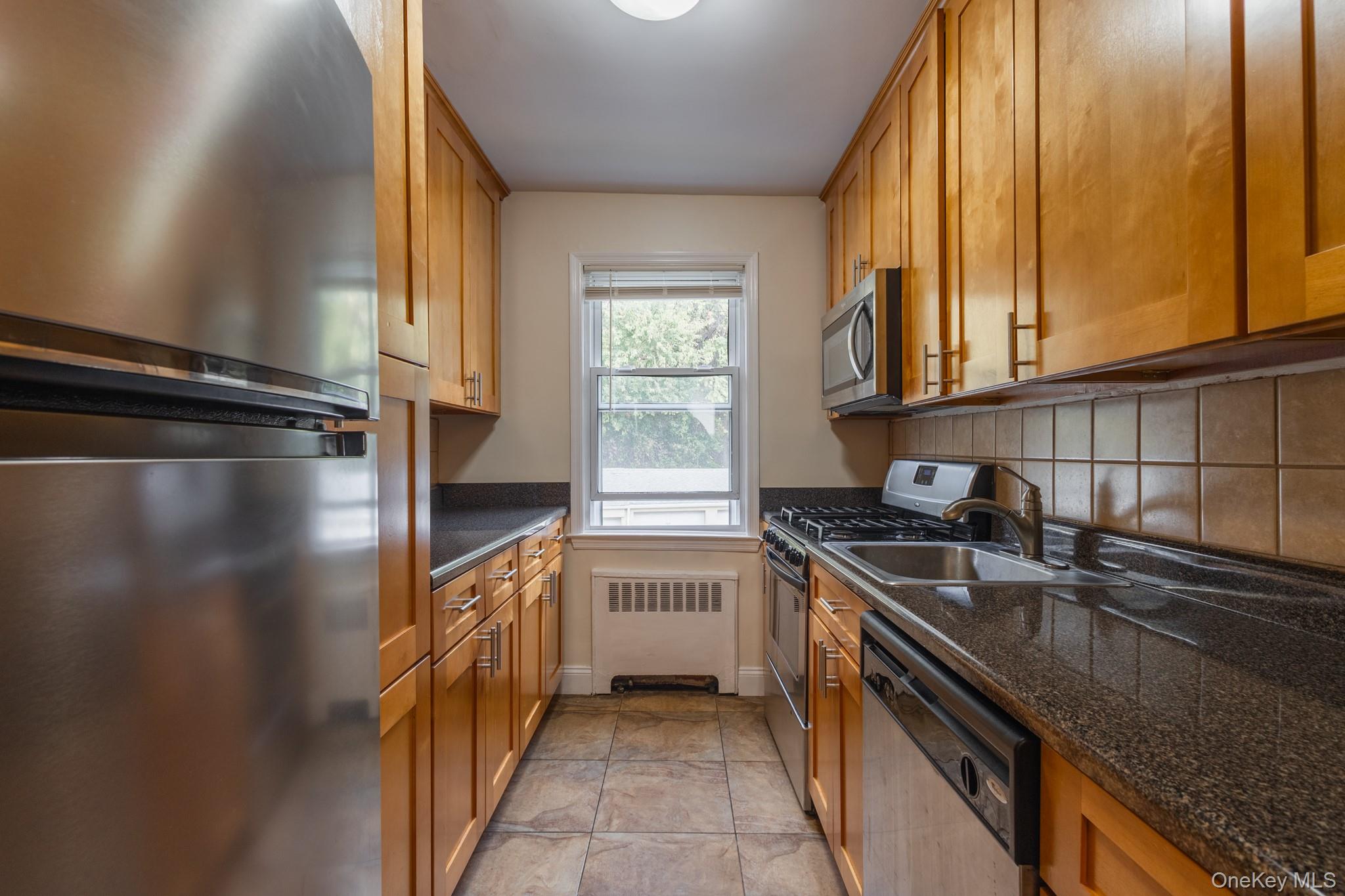251-41 71st Road, Unit 54B Queens, NY 11426 - Photo 10 of 20 a kitchen with a sink a counter top space cabinets and stainless steel appliances