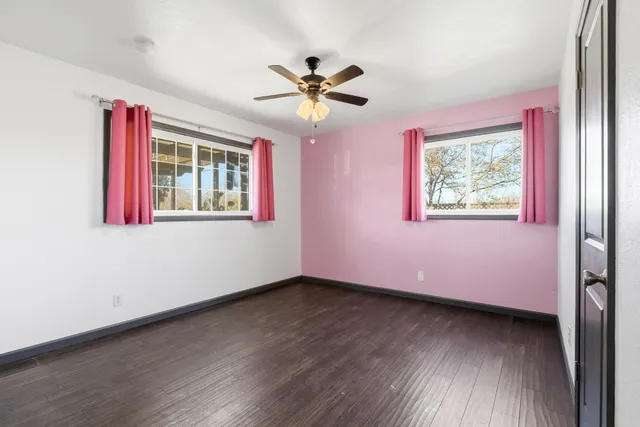 a view of a livingroom with wooden floor a ceiling fan and a window