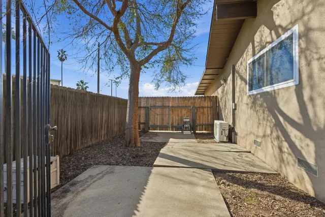 a view of a brick house with a small yard and wooden fence