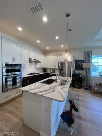 a kitchen with granite countertop a table chairs a sink dishwasher window and cabinets