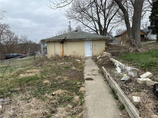 a backyard of a house with large trees and outdoor seating