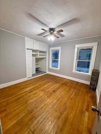 a view of an empty room with a fireplace and a ceiling fan