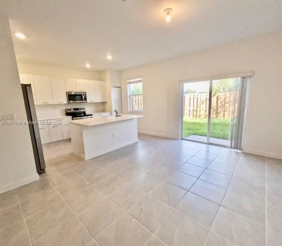 a kitchen with stainless steel appliances a sink a stove a refrigerator a window