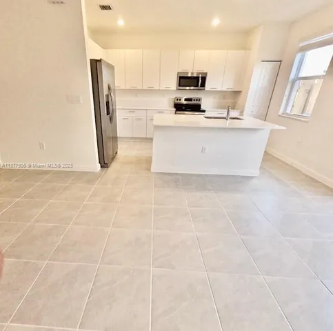 a view of kitchen with stainless steel appliances a sink a stove a microwave a counter top space and cabinets