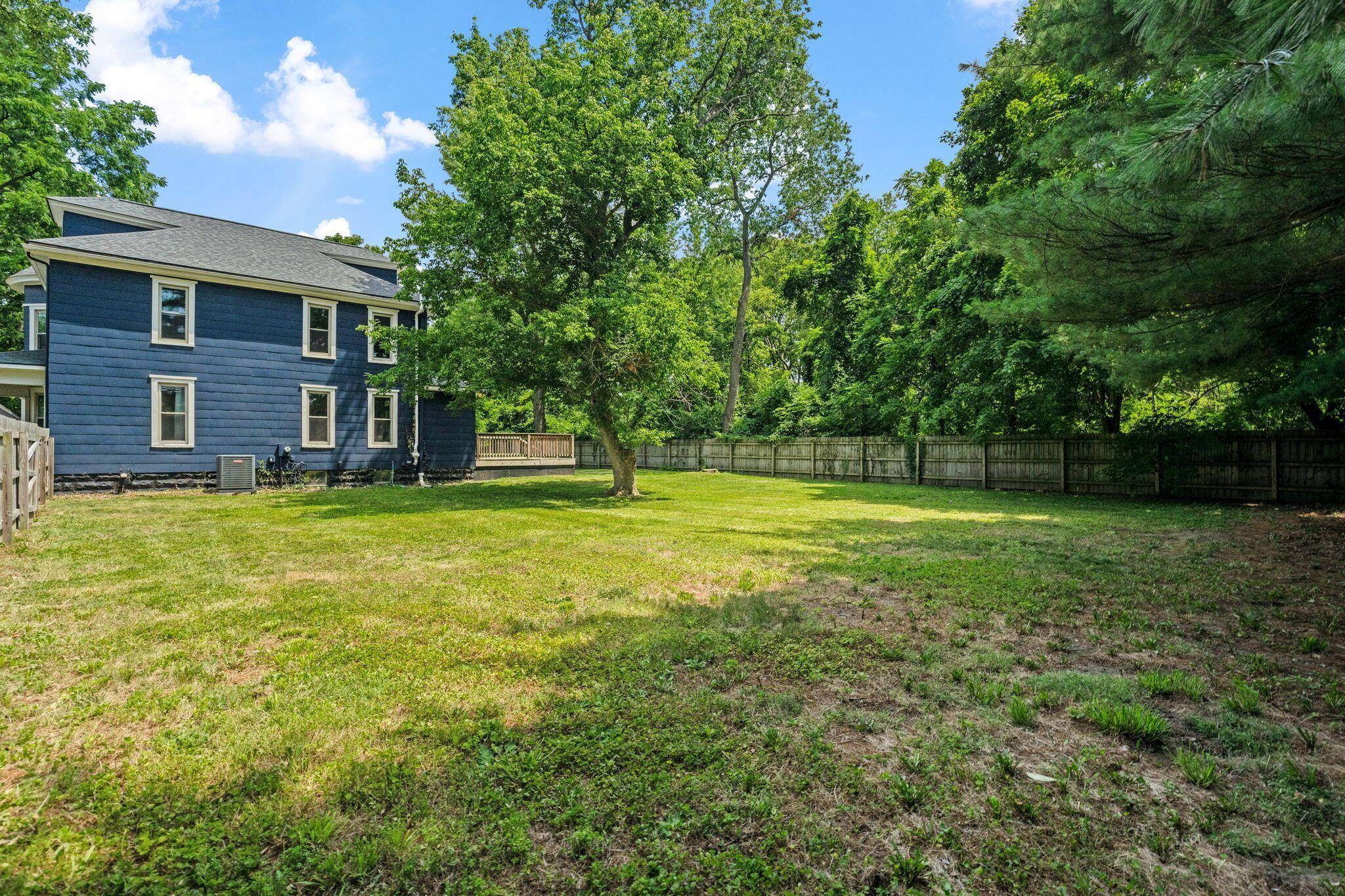 107 Price Road Columbus, OH 43230 - Photo 36 of 51 Expansive green lawn with mature trees and a wooden privacy fence bordering the property
