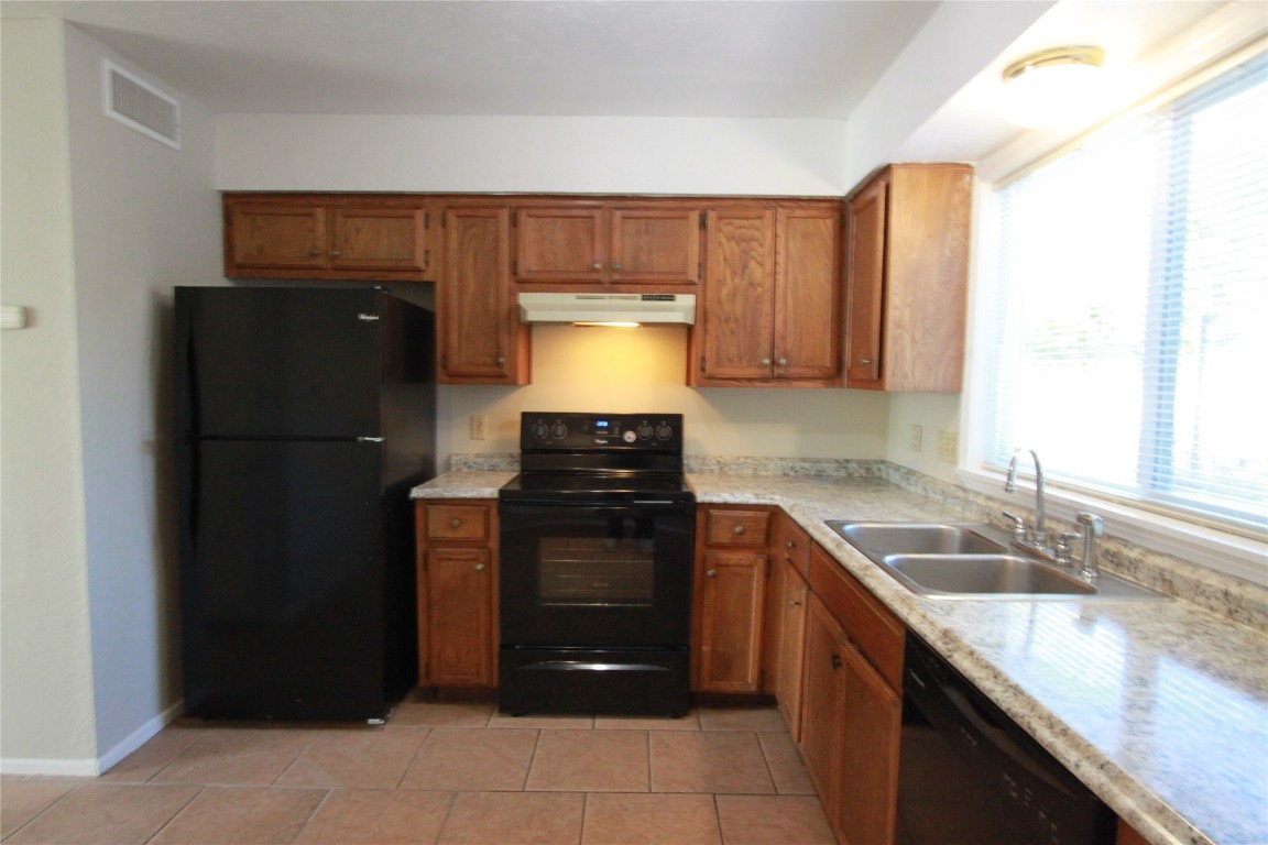 3904 Hudson Bend Road, Unit D Austin, TX 78734 - Photo 11 of 25 Kitchen featuring black appliances, brown cabinets, under cabinet range hood, and light tile patterned flooring