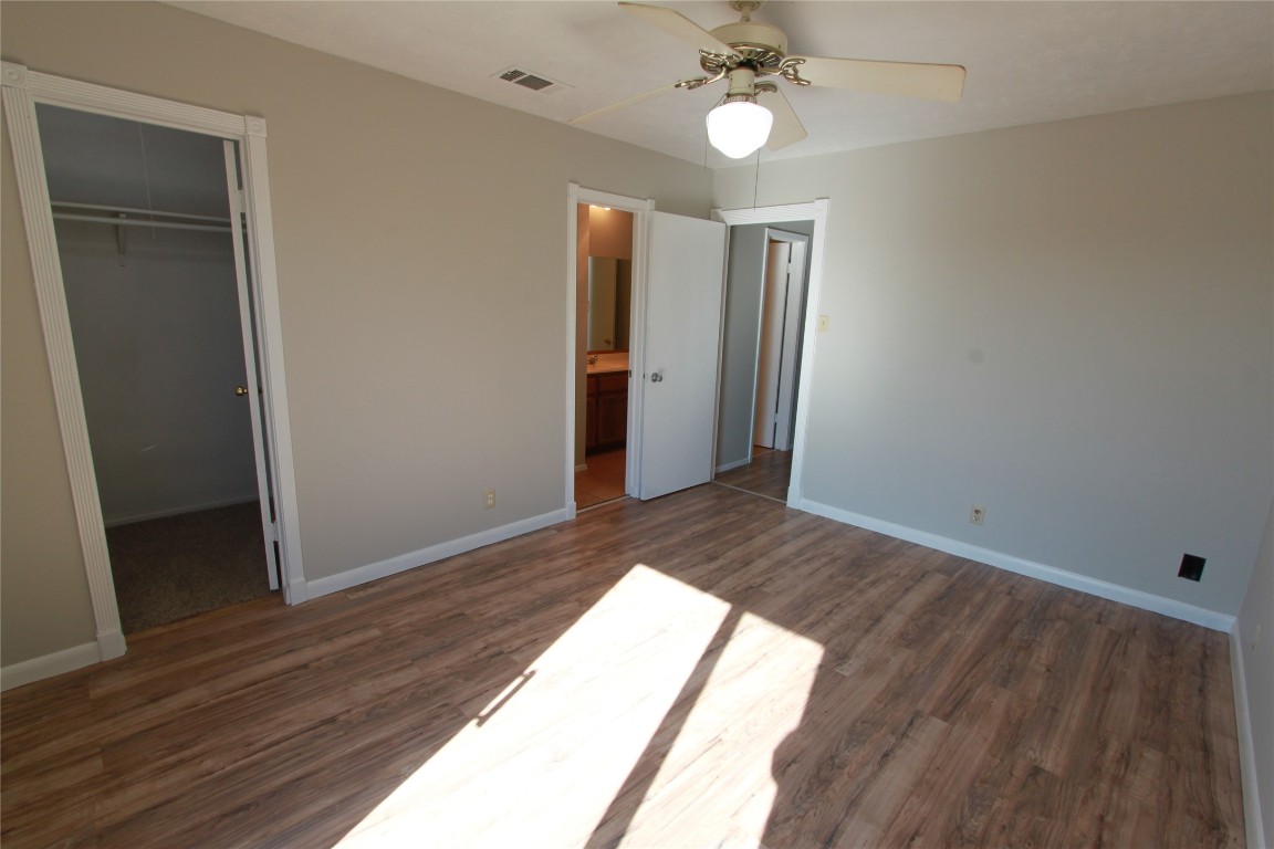 3904 Hudson Bend Road, Unit D Austin, TX 78734 - Photo 18 of 25 Unfurnished bedroom featuring a walk in closet, dark wood-style flooring, and ceiling fan