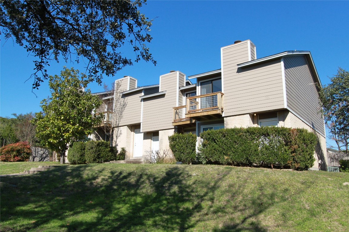 3904 Hudson Bend Road, Unit D Austin, TX 78734 - Photo 2 of 25 Rear view of property featuring a balcony, a yard, brick siding, and a chimney