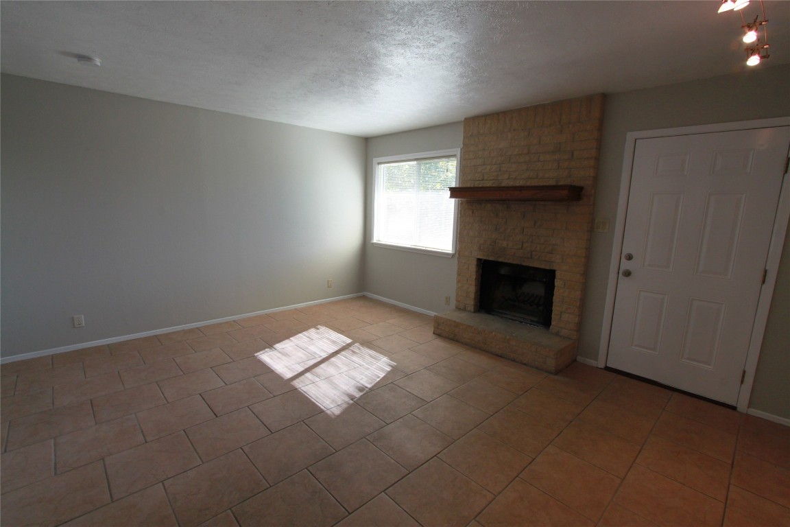3904 Hudson Bend Road, Unit D Austin, TX 78734 - Photo 7 of 25 Unfurnished living room featuring a fireplace, a textured ceiling, and light tile patterned flooring