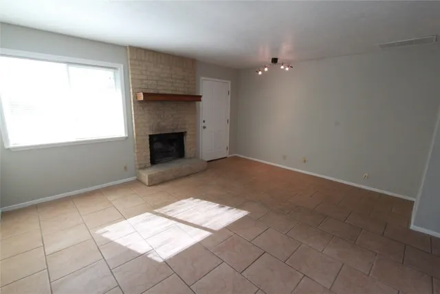 an empty room with windows and fireplace