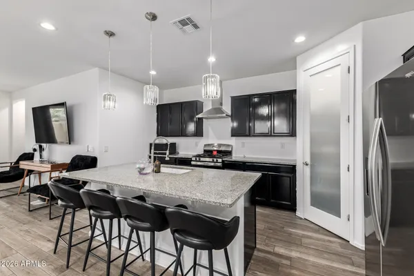 a kitchen with granite countertop a refrigerator a stove a sink a dining table and chairs with wooden floor