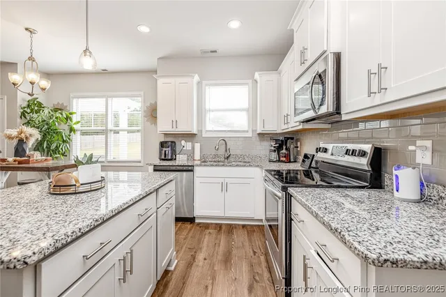 a kitchen with stainless steel appliances granite countertop a sink stove and cabinets