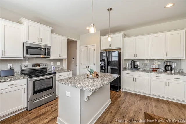 a kitchen with kitchen island granite countertop stainless steel appliances a stove sink microwave and cabinets