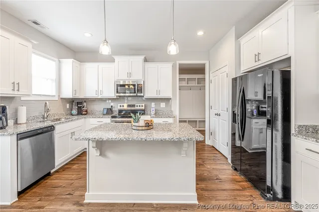 a kitchen with stainless steel appliances granite countertop a refrigerator a sink a stove and oven