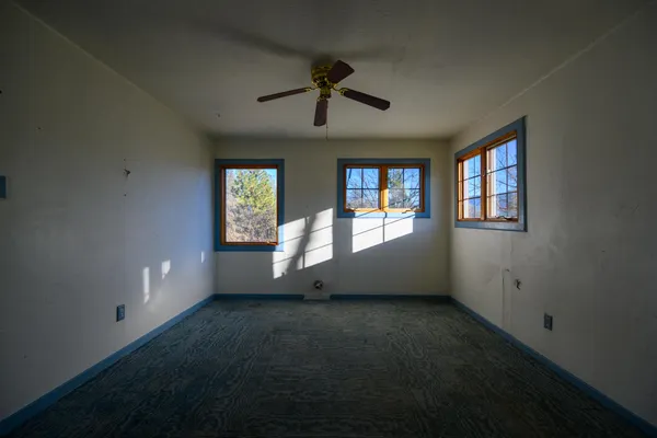 an empty room with windows and ceiling fan