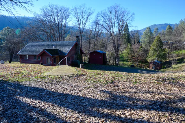 a view of a wooden house with a yard covered with snow