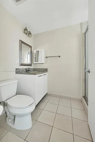 a bathroom with a granite countertop toilet a sink and mirror