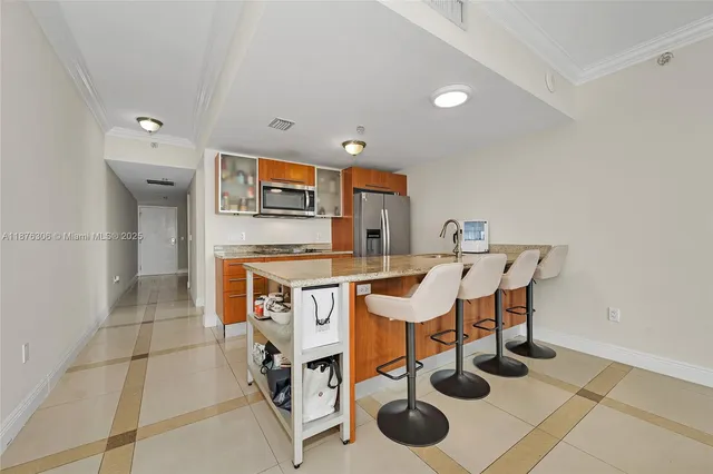 a kitchen with stainless steel appliances kitchen island granite countertop a sink and a refrigerator