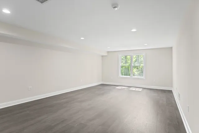 an empty room with wooden floor and window