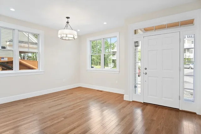 an empty room with wooden floor chandelier and windows