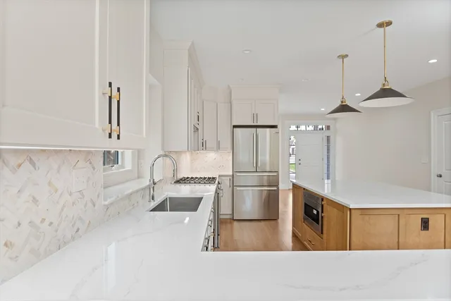 a kitchen with stainless steel appliances a refrigerator a sink and white cabinets