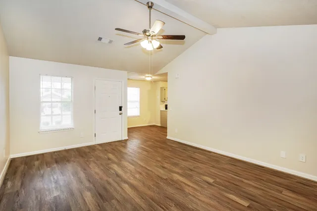 an empty room with wooden floor and windows