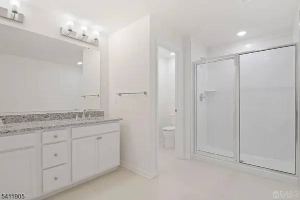 a bathroom with a granite countertop sink two mirror and a shower