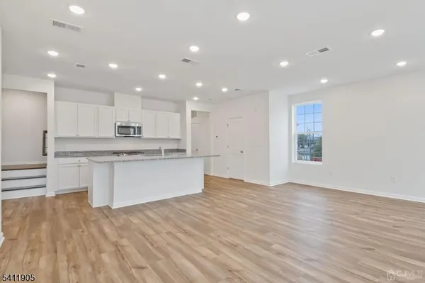 a large kitchen with kitchen island a sink dishwasher a stove and white cabinets with wooden floor