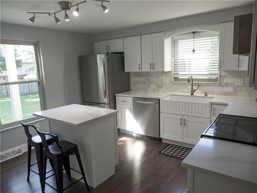 102 Bertley Ridge Drive Coraopolis, PA 15108 - Photo 7 of 25 a kitchen with stainless steel appliances a stove a refrigerator a sink a dining table and chairs with wooden floor