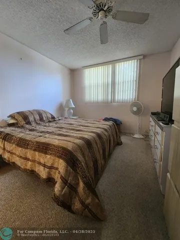a bedroom with a bed and flat tv screen on the dresser